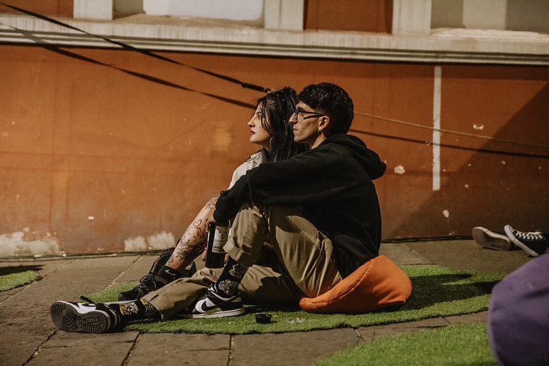 Pareja sentada en la Calle 10 frente a la FUGA observando una película.